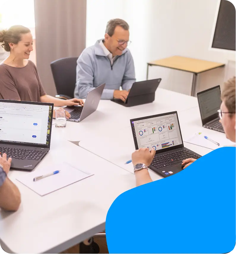 Teammeeting mit Laptops im hellen Konferenzraum.